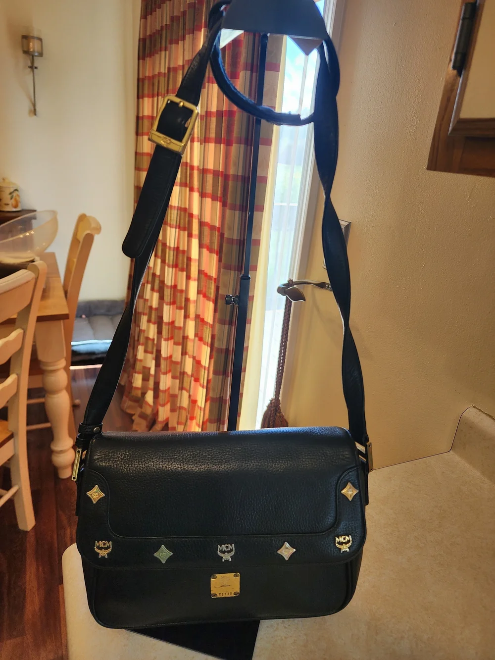 vintage MCM black pebbled leather studded crossbody bag featuring a front plaque